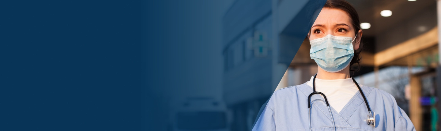 Health care worker wearing a protective mask outside a medical facility representing response and preparedness during public health emergencies
